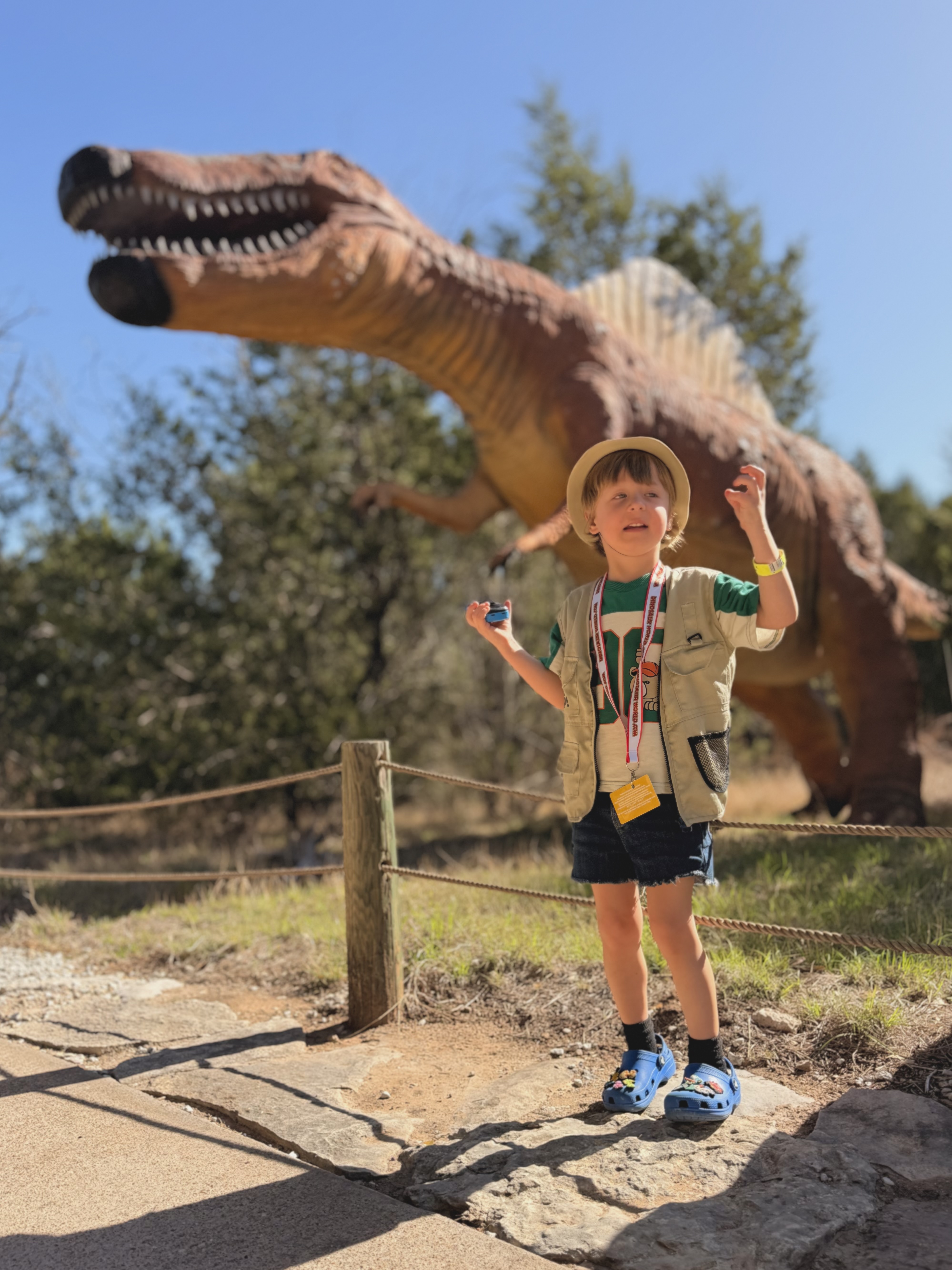 Gus in front of the Spinosaurus, arms raised