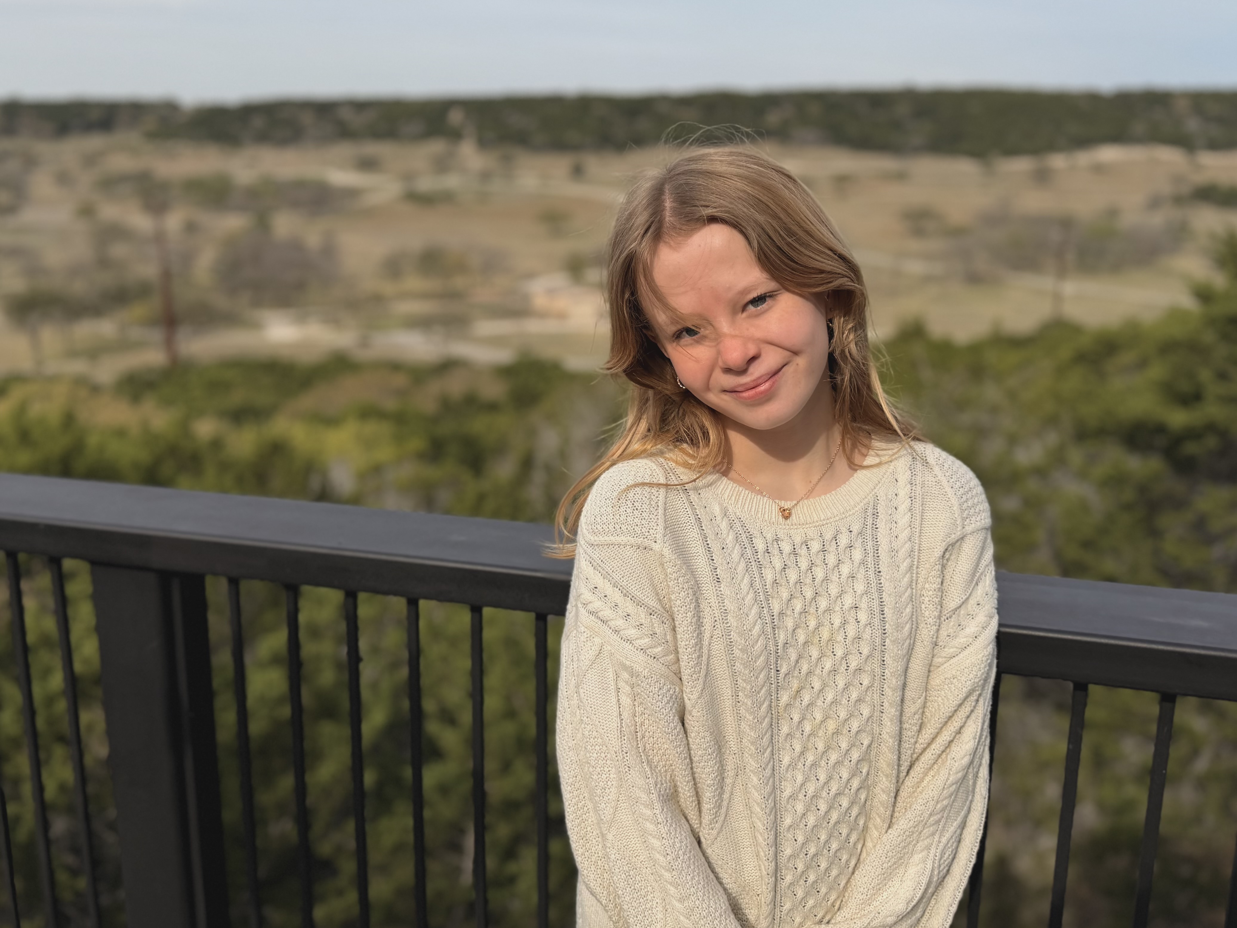 Ruby at the Fossil Rim overlook, hair blowing, rolling hill country landscape behind her