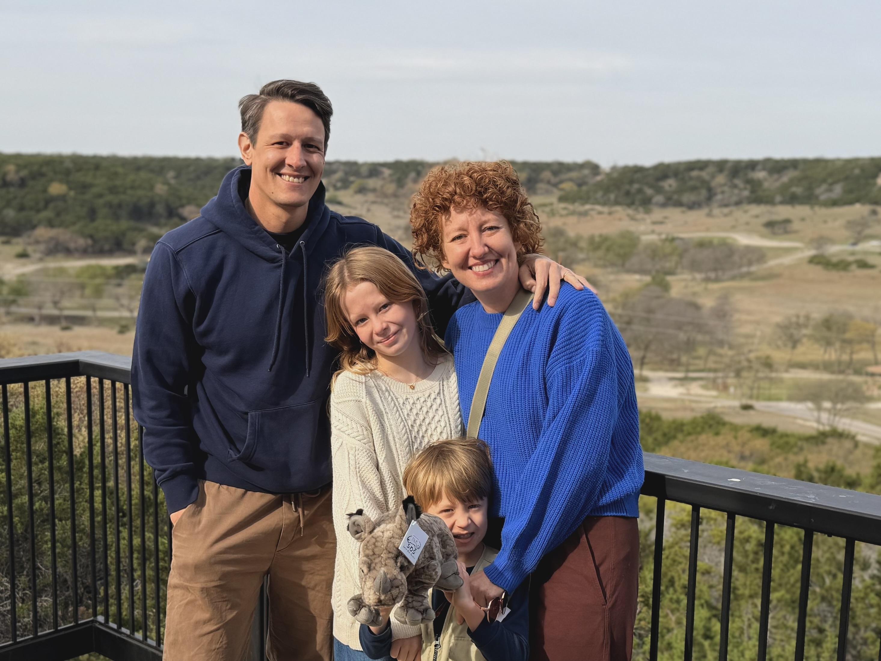 Johnson family at the Fossil Rim overlook — Jarad, Ruby, Laura, and Gus holding his new stuffed rhinoceros